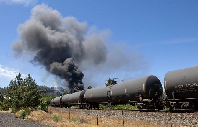 A train carrying Bakken crude oil, a type of oil known to be highly volatile, sits alongside a public parking area in downtown Mosier after derailing and catching fire around noon on Friday. (Mark Gibson photo)