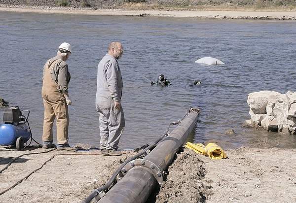 (Dan Wheat photo) Paul Gray and Chris Sauer, of Gray's Electric, Wenatchee, Wash., watch divers in Columbia River helping install new 12-inch irrigation pipe on April 18. Water was to start flowing April 21 to the Washington State University Sunrise and Piepel Premium Fruit orchards.